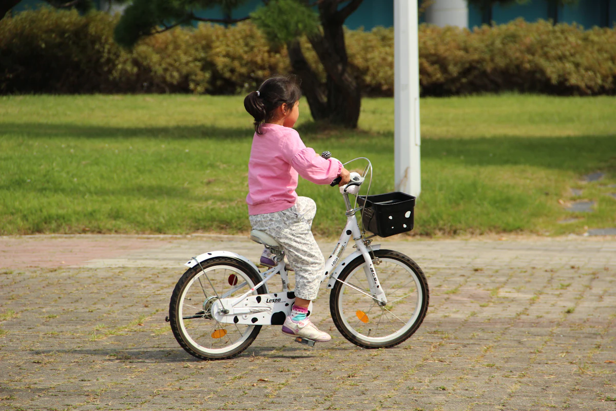 A young girl riding a small white bike with a basket